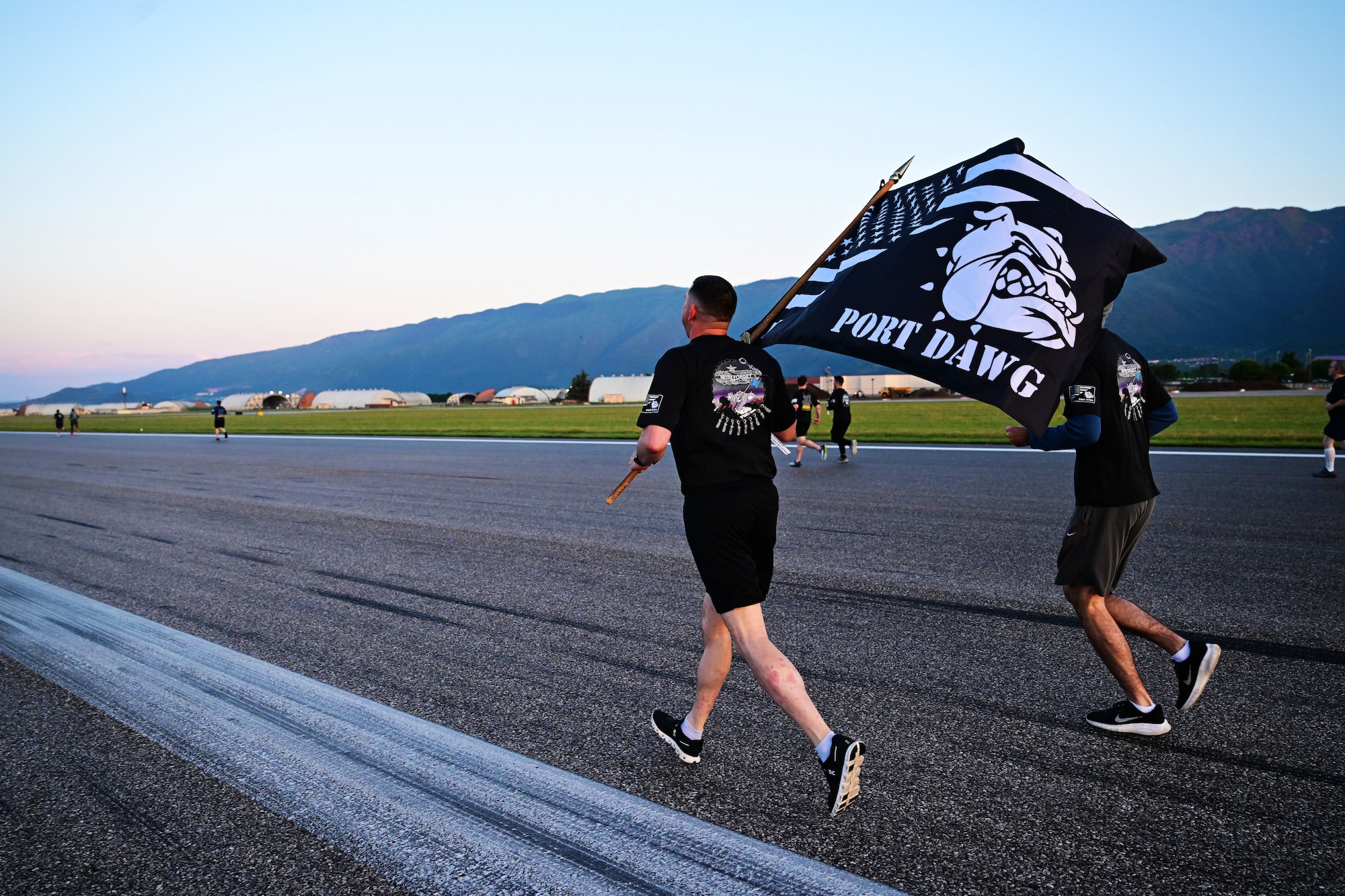 A man runs down the flightline with a port dawg flag