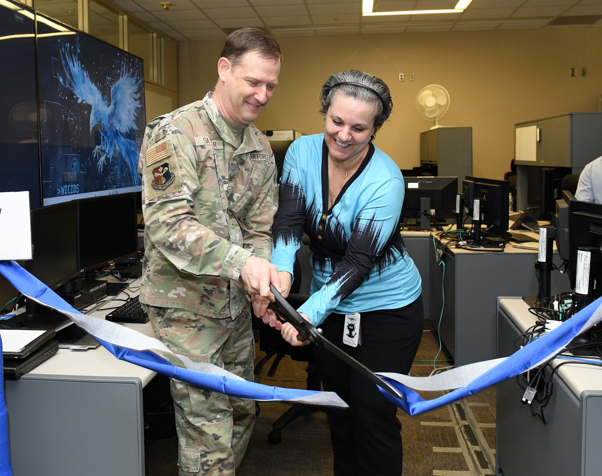Air Force Colonel and civilian cut a ribbon during an activation ceremony.