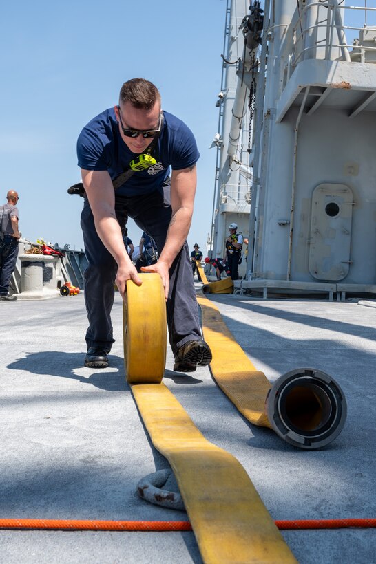 Fireman rolls up a water hose. (U.S. Air Force photo by Airman 1st Class Donnell Ramsey)