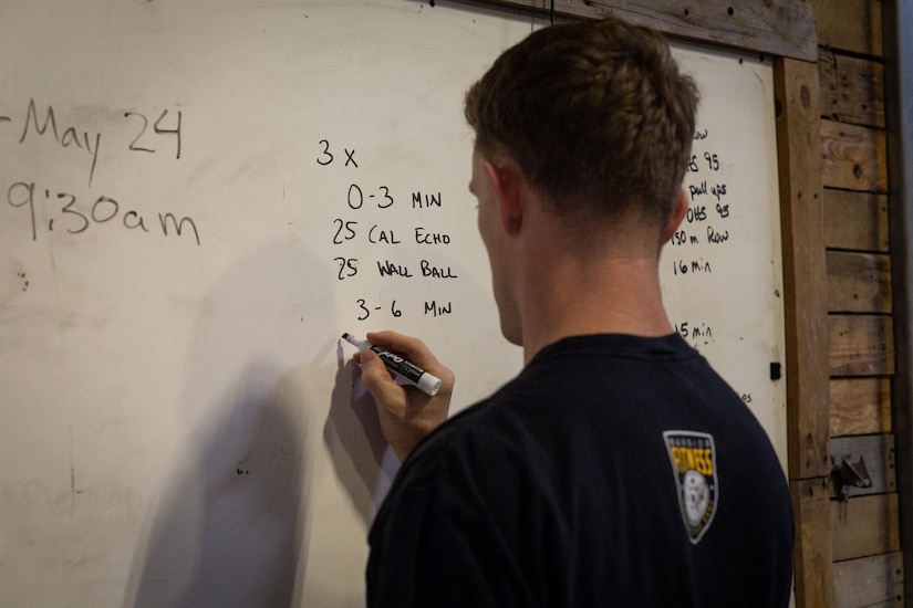 1st Lt. Erik Thomas writes his workout routine on a white board at CrossFit Frankfort in Frankfort, Ky., May 15, 2025.