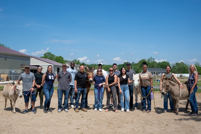 Airmen from Air Force Mortuary Affairs Operations pose with farm animals and equine-therapy coaches for a group photo.