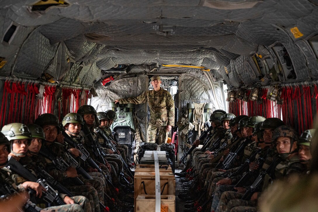A group of Honduran and El Salvadoran service members listen to a briefing while a U.S. service member stands in the back