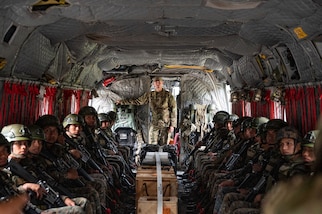 A group of Honduran and El Salvadoran service members listen to a briefing while a U.S. service member stands in the back