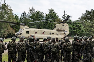 A group of Honduran and El Salvadorian soldiers look at a U.S. helicopter