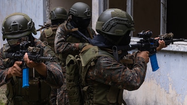Guatemalan service members hold rifles while preparing to clear a building