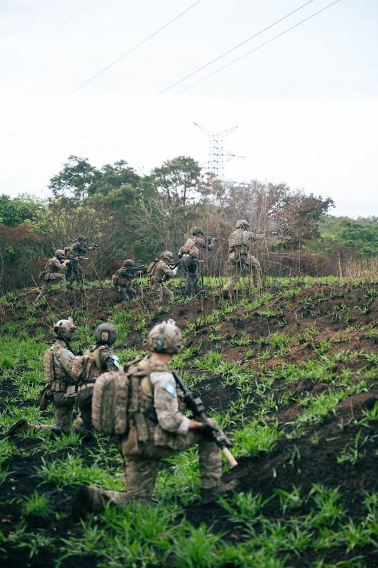 U.S. and Guatemalan service members stand and kneel in a field