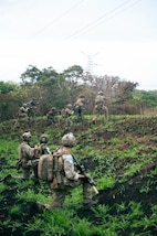 U.S. and Guatemalan service members stand and kneel in a field