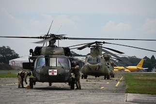 Two U.S. helicopters sit on a tarmac after landing in Guatemala