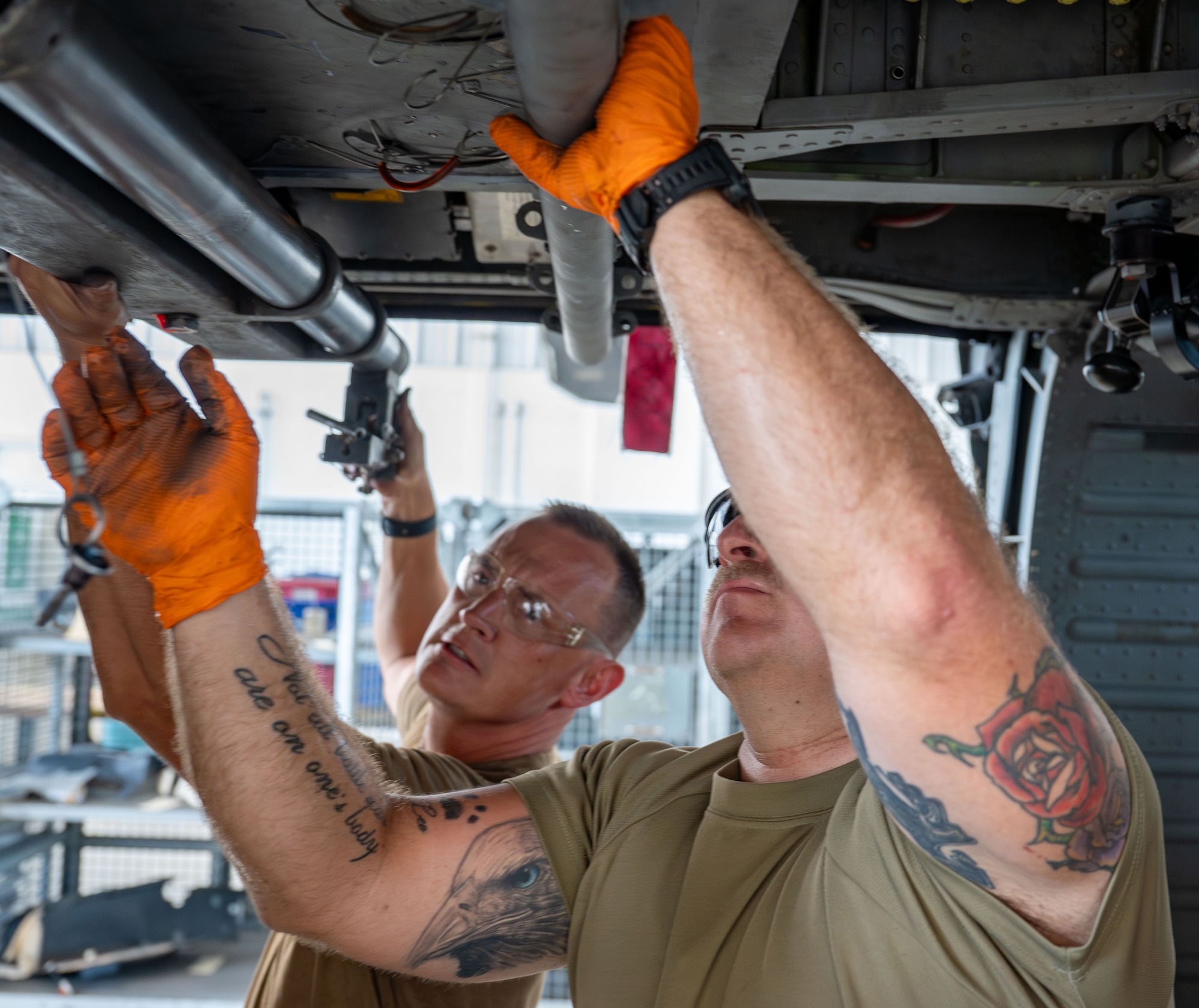 Master Sgt. James Wilcons and Senior Airman Sean Krebs reinstall the Fast Rope Insertion/Extraction System bar