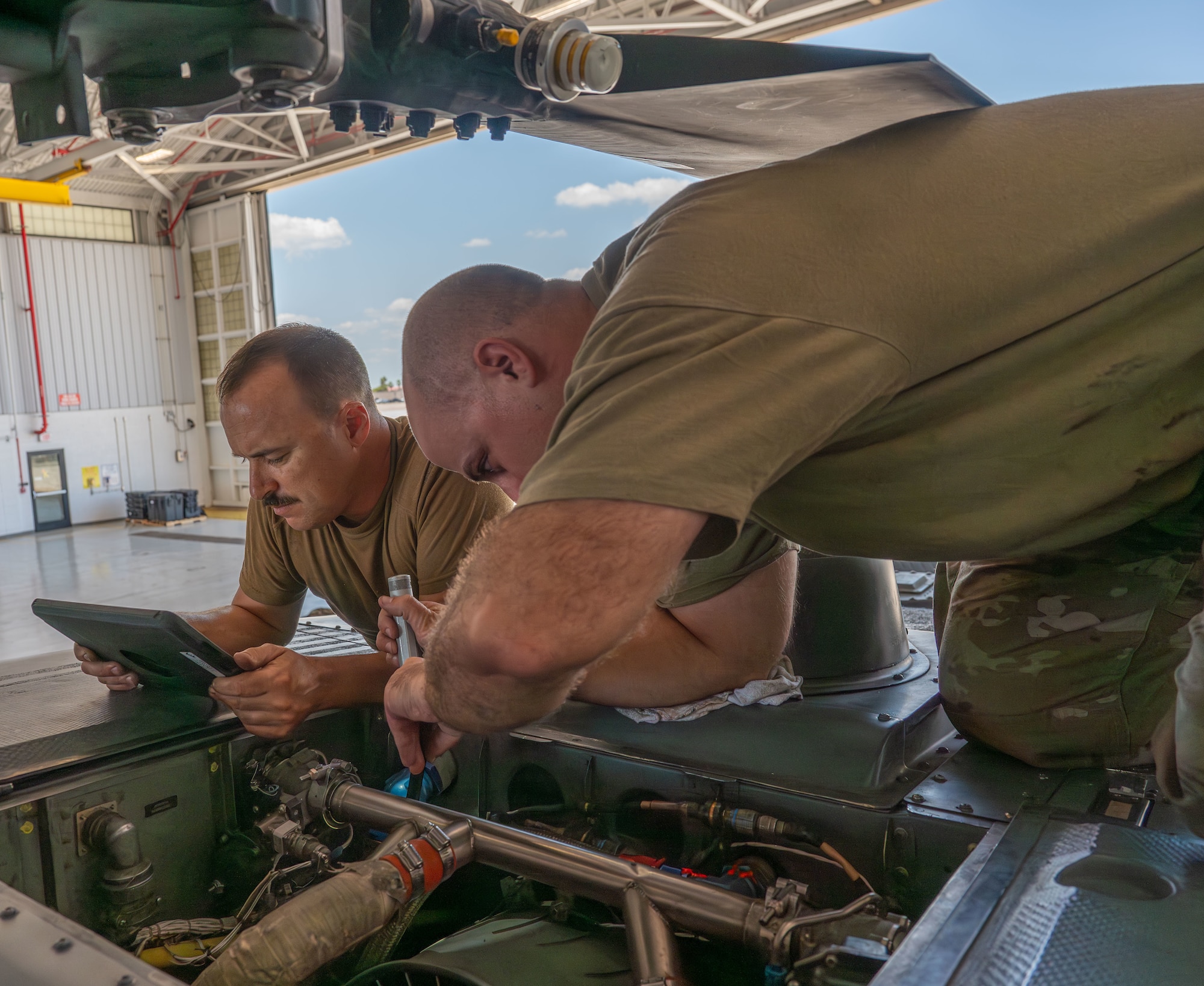 Senior Airman David Miyamoto and Tech. Sgt. Nicholas Barbieri inspect the oil cooler