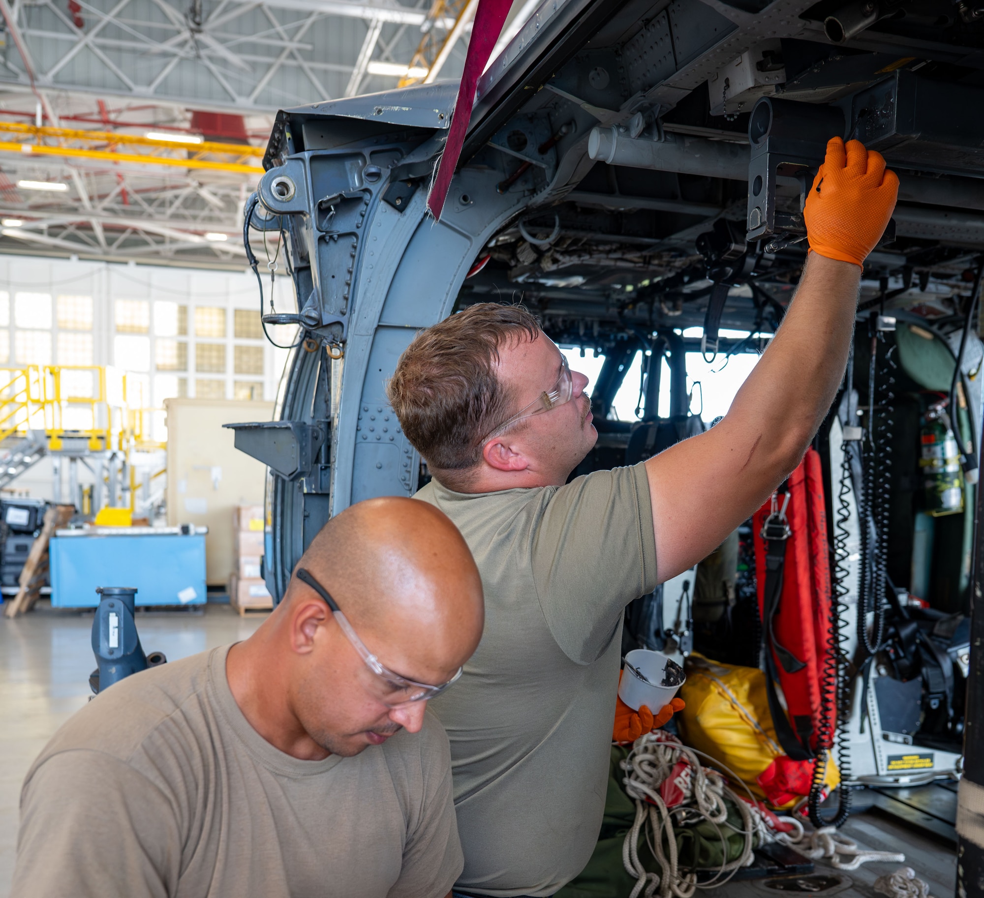 Staff Sgt. Campbell Lawton and Staff Sgt. Manuel Rodriguez-Sepulveda mix and apply sealant to the Fast Rope Insertion/Extraction System bar