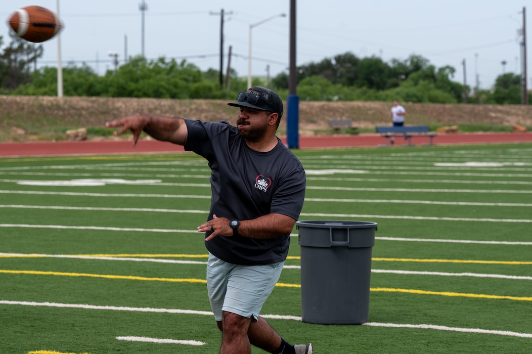A Defender Challenge participant throws a football as part of the physical fitness challenges included in the Defender Challenge at the Mathis Fitness Center track, Goodfellow Air Force Base, Texas, May 14, 2025.  The 17th Security Forces Squadron observed National Police Week from May 12–16.  (U.S. Air Force photo by Airman 1st Class James Salellas)