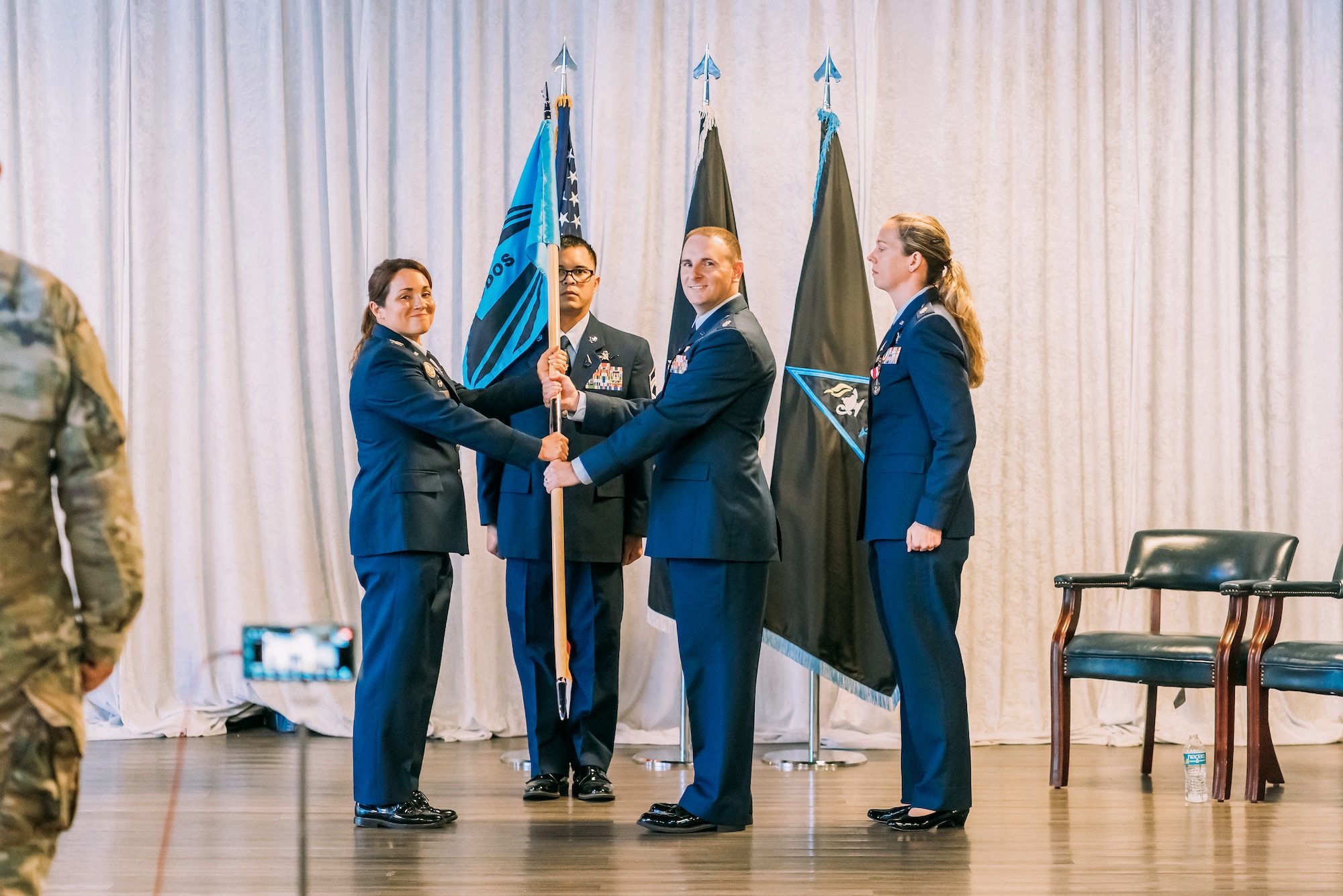U.S. Space Force Col. S. Shannon DaSilva, commander of Space Delta 10, Space Training and Readiness Command, left, passes a guidon to Lt. Col. Justin Jones, middle, during a change of command ceremony. Outgoing commander Lt. Col. Sheena Mira stands behind him on the right.