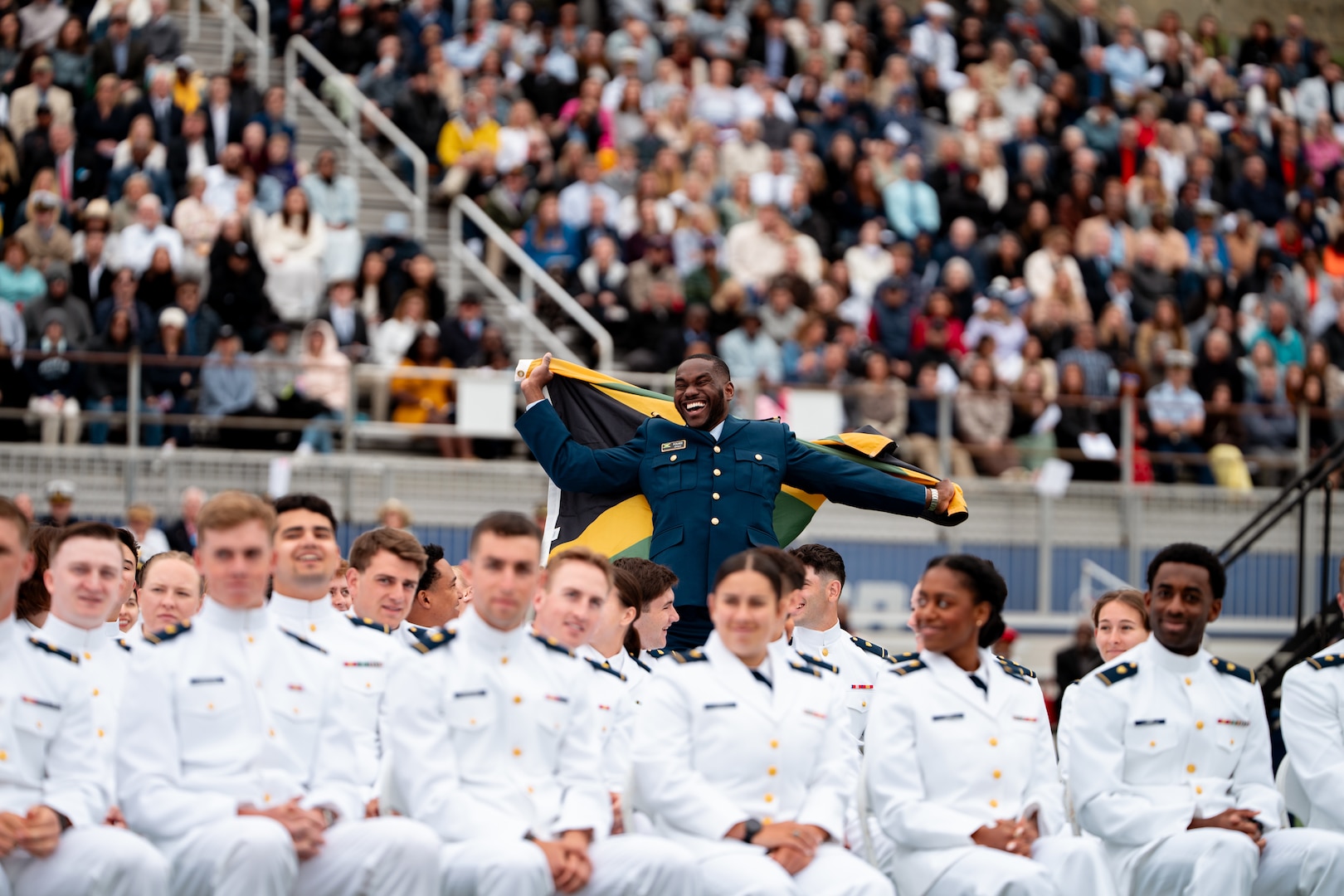 U.S. Coast Guard Academy (USCGA) international Jamaican Cadet Nicholas Folkes waves a Jamaican flag during the 144th Commencement Exercises at USCGA, May 21, 2025. USCGA graduated multiple international cadets, who will return to their home nations to serve in various militaries and organizations. (U.S. Coast Guard photo by Petty Officer 3rd Class Matt Thieme.)