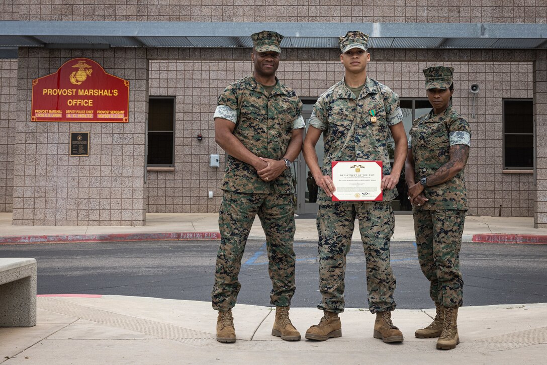 U.S. Marine Corps Brig. Gen. Nick Brown and Sgt. Maj. Sherri Cook, the commanding general and senior enlisted leader of Marine Corps Installations West, Marine Corps Base Camp Pendleton, pose for a photo with Lance Cpl. Marcus Benson, a military police augment with Provost Marshal Office, MCIW, MCB Camp Pendleton, center, on MCB Camp Pendleton, Calif., April 15, 2025. Benson, a Texas native, received an award for ending an active police pursuit on March 3, 2025. (U.S. Marine Corps photo by Cpl. Jacqueline Akamelu)