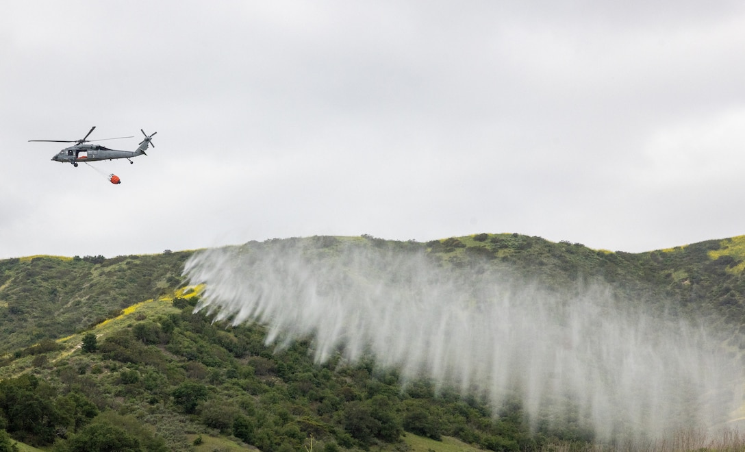 U.S. Navy MH-60 Sea Hawk with Helicopter Sea Combat Squadron 3, Naval Air Station North Island, expels water from a “Bambi” firefighting bucket over a target area during the annual Cory Iverson Wildland Firefighting exercise at Las Pulgas Lake, Marine corps Base Camp Pendleton, Calif., May 1, 2025. The Cory Iverson Wildland firefighting exercise is an annual event focusing on interagency cooperation between the California Department of Forestry and Fire Protection, San Diego County Sheriff’s Department, the Camp Pendleton Fire Department and the Department of Defense. During the exercise, each entity works together to create an effective, efficient and well-trained team with local, state and federal partner agencies to provide mutual aid to best protect installations within Marine Corps Installations West and their surrounding local communities. (U.S. Marine Corps photo by Cpl. Jacqueline Akamelu)
