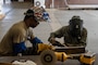 Two U.S. Air Force Airmen look over a piece of metal before performing a welding task in their shop.