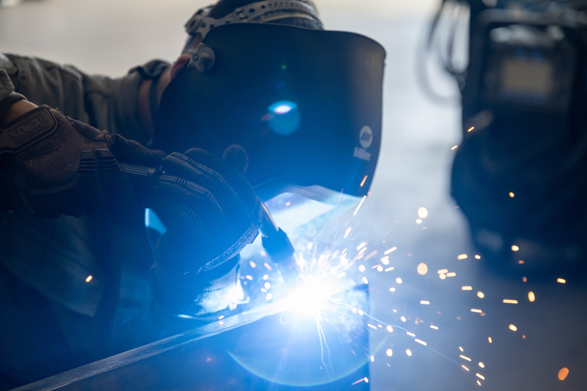 A U.S. Air Force Airmen welds a piece of metal as part of an aircraft part.
