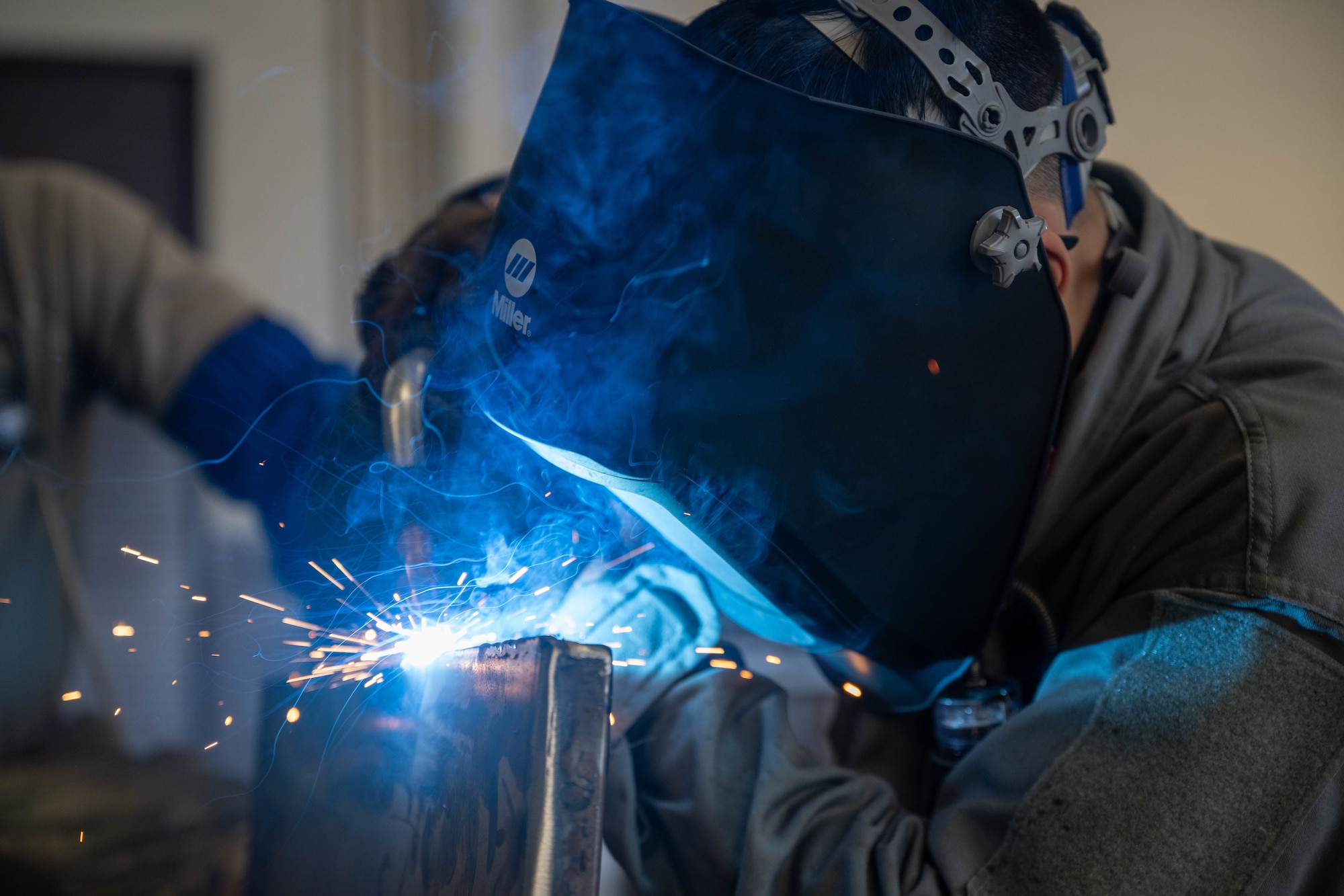 A U.S. Air Force Airmen welds a piece of metal as part of an aircraft part.