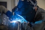A U.S. Air Force Airmen welds a piece of metal as part of an aircraft part.