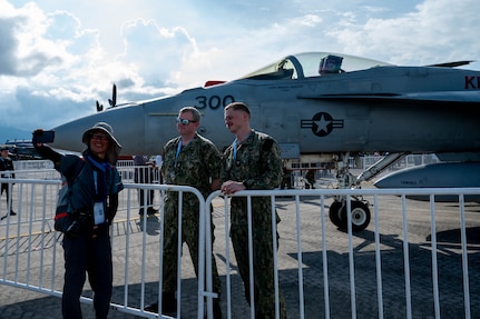 Senior Chief Aviation Electrician's Mate Richard Tretsven, left, and Aviation Electrician's Mate Second Class Marcus Cox pose for a photo in front of an F/A-18E Super Hornet from the “Kestrels” of Strike Fighter Squadron (VFA) 137 with an attendee at the Langkawi International Maritime and Aerospace Exhibition 2025 in Langkawi, Malaysia, May 20, 2025. LIMA 25 is a biennial event that brings together industry stakeholders and government and military leaders from more than a dozen nations for a five-day event dedicated to the maritime and aerospace sectors for defense, civil and commercial applications. (U.S. Air Force photo by Senior Airman Alexzandra Gracey)
