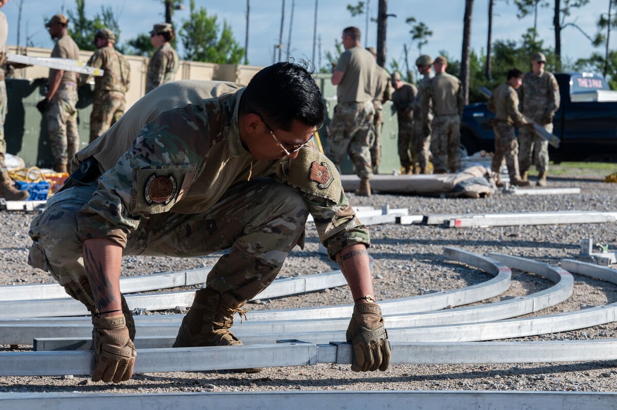 U.S. Air Force Senior Airman Matthew Montillo, 7th Security Forces Squadron patrolman, aligns tent frames during exercise CHAOS RISING at Tyndall Air Force Base, Florida, May 10, 2025. The training exercise occurred at a Combat Support Training Range and allowed the 21st Air Task Force to exercise command and control elements using an Agile Combat Employment design rather than a traditional beddown, enhancing their flexibility and mobility. (U.S. Air Force photo by Senior Airman Alondra Cristobal Hernandez)