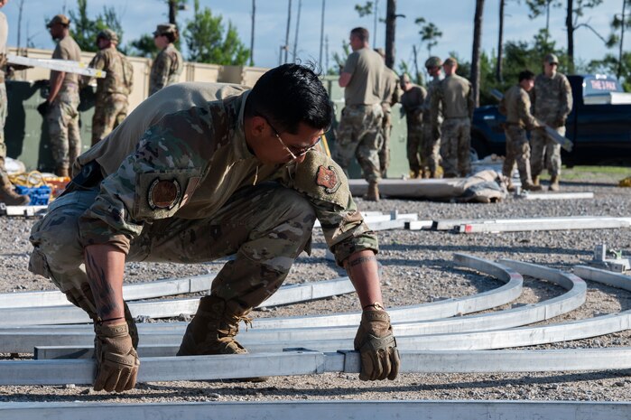 U.S. Air Force Senior Airman Matthew Montillo, 7th Security Forces Squadron patrolman, aligns tent frames during exercise CHAOS RISING at Tyndall Air Force Base, Florida, May 10, 2025. The training exercise occurred at a Combat Support Training Range and allowed the 21st Air Task Force to exercise command and control elements using an Agile Combat Employment design rather than a traditional beddown, enhancing their flexibility and mobility. (U.S. Air Force photo by Senior Airman Alondra Cristobal Hernandez)