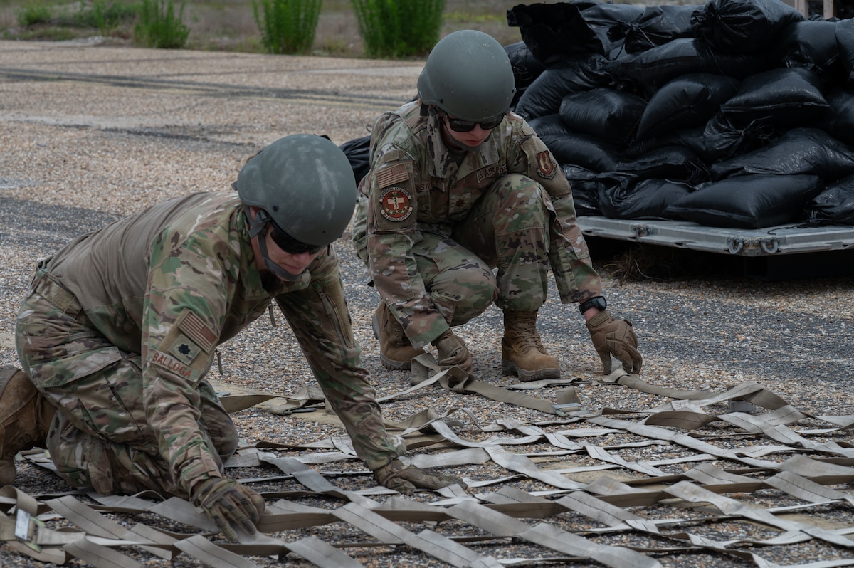 U.S. Air Force Lt. Col. Sarah Balloga, 96th Medical Support Squadron health care associate program director, and Maj. Mary Storey, 96th Medical Support Squadron laboratory and pathology flight commander, lay pallet netting as part of a pallet mobilization course during exercise CHAOS RISING at a Combat Support Training Range location, Tyndall Air Force Base, Florida, May 9, 2025. The 21st Air Task Force participated in rigorous exercises and diverse training programs to ensure the ATF is fully prepared to execute assigned missions. (U.S. Air Force photo by Senior Airman Alondra Cristobal Hernandez)