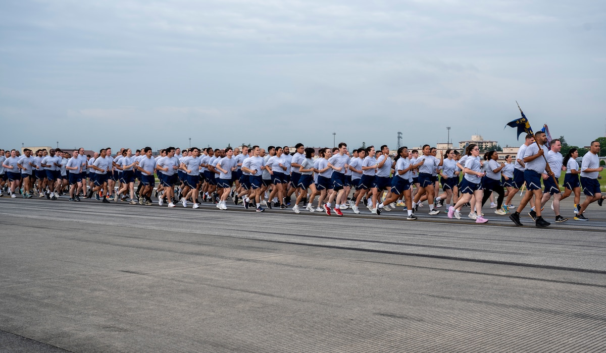 Military members run in formation on a flightline.