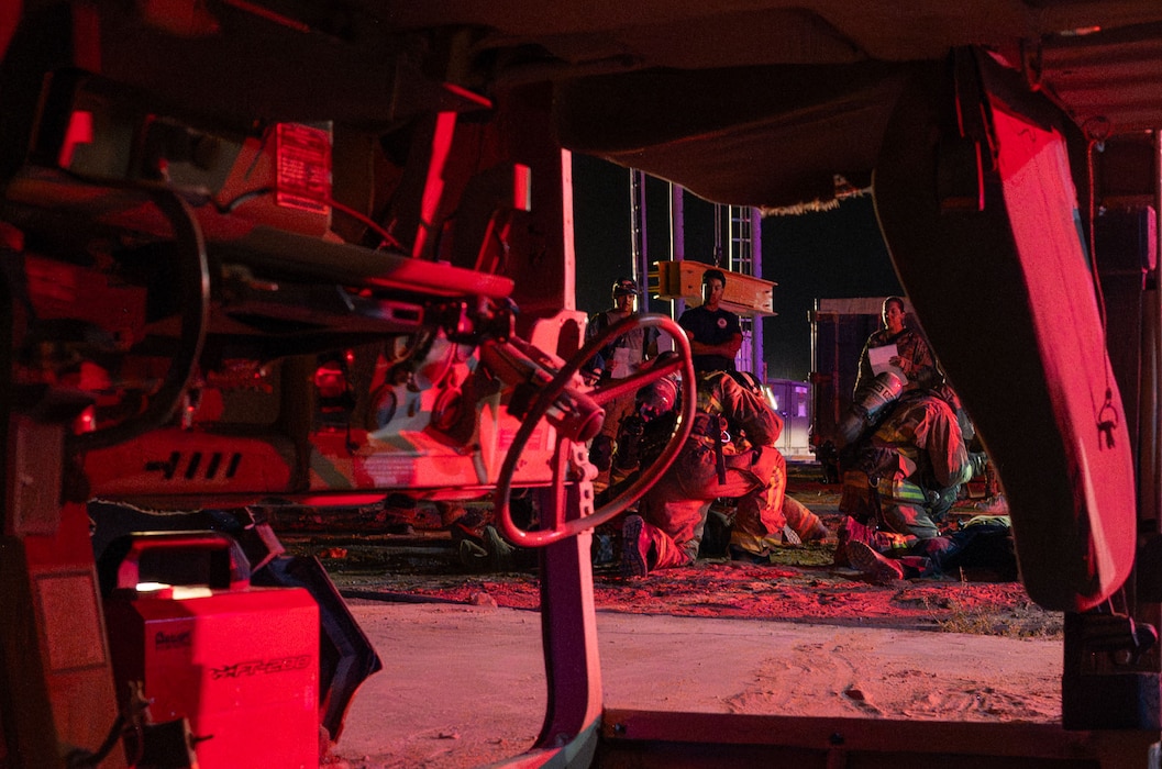 First responders are shown treating a simulated casualty through the frame of a rolled Humvee.