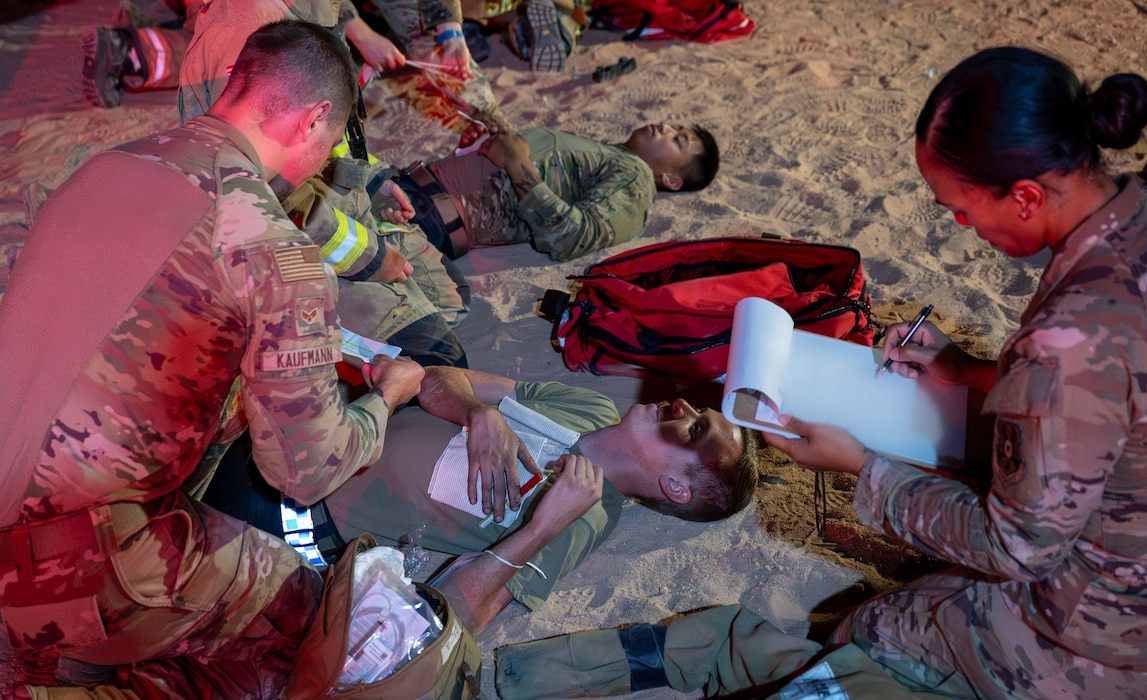 A medic attends to a simulated casualty while a trainer assesses the care provided.