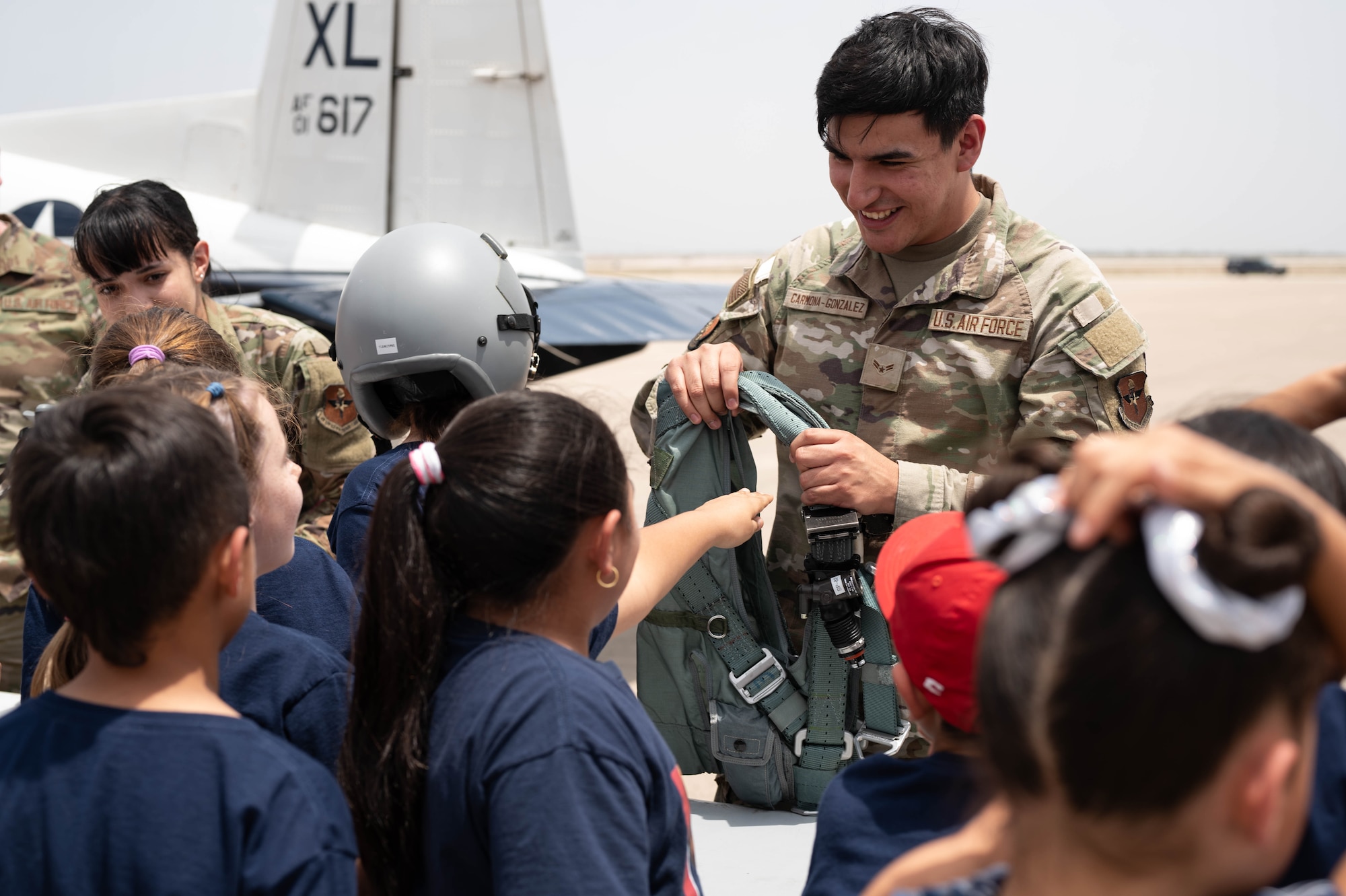 Senior Airman Elijah Aryan Carmona-Gonzalez, 47th Operation Support Group aircrew flight equipment technician, shows students a pilot harness during a Ceniza Hills School tour at Laughlin Air Force Base, Texas, May 15, 2025. Students got a glimpse at the critical support roles behind Laughlin’s pilot training mission. (U.S. Air Force photo by Senior Airman Keira Rossman)