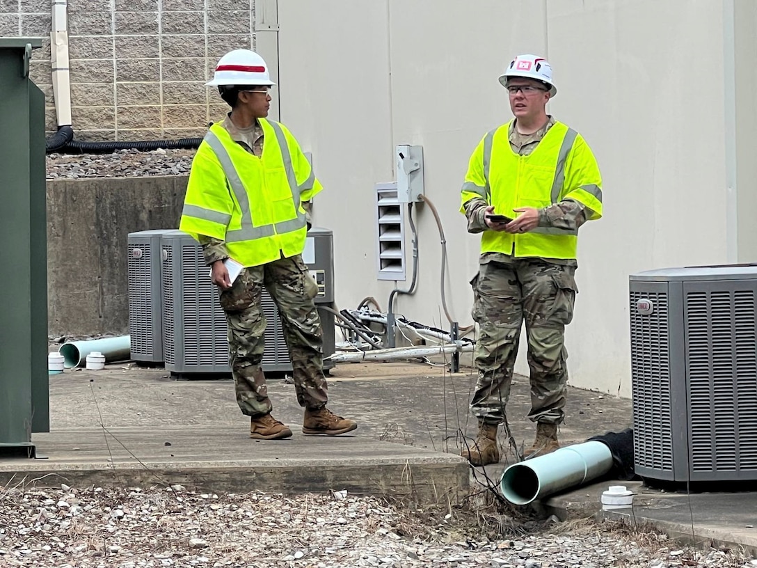 Two soldiers stand near air conditioning units after they