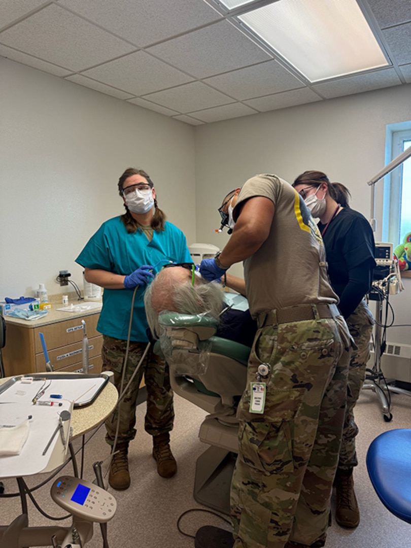 Capt. Miguel Velez, a dentist with the New Hampshire Army National Guard Medical Readiness Detachment (MED DET), receives assistance from Sgt. 1st Class Kelly James, a dental hygienist with MED DET, and Tech. Sgt. Dakota Vondrasek, an operational medicine medic of the 157th Air Refueling Wing, New Hampshire Air National Guard, while performing dental work on a patient during Operation Arctic Care, April 10, 2025, in Selawik, Alaska.