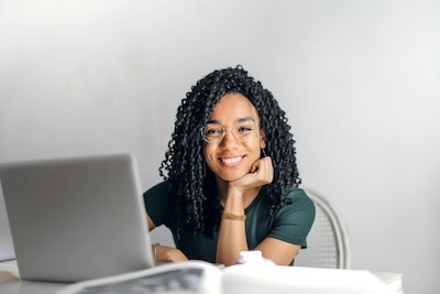 Woman smiles while working on a laptop.