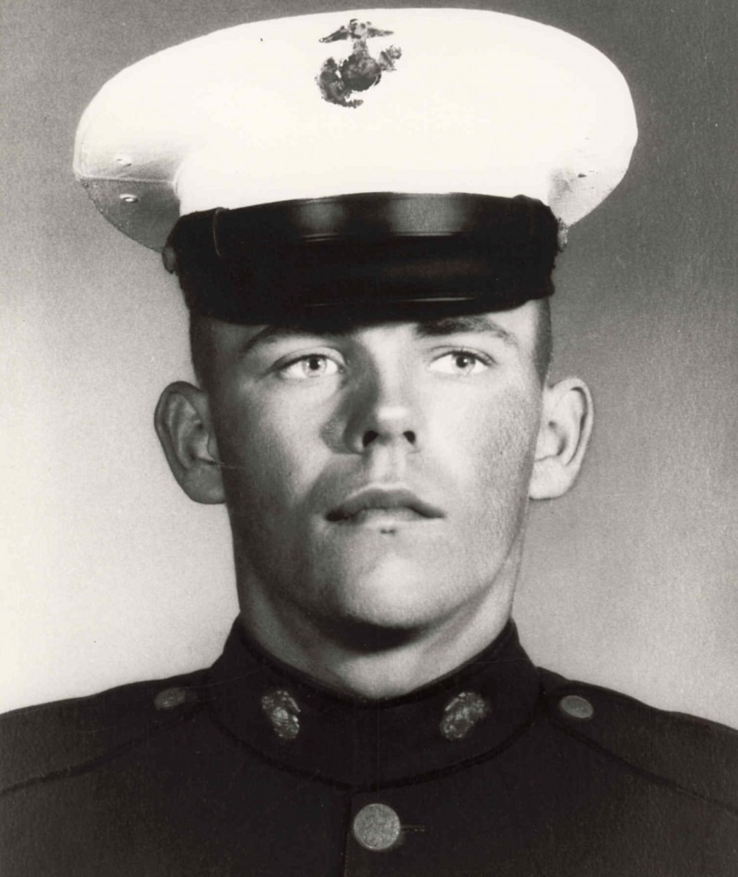 A man wearing a military uniform and cap poses for a photo.