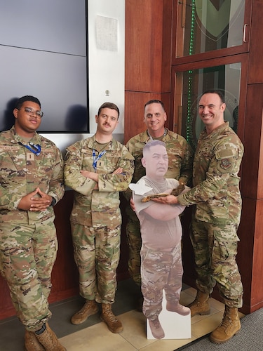 The Air Mobility Command Rapid Innovation Team poses for a photo with a cutout of Lt. Col. Loc Nguyen, Air Mobility Command advanced analytic division chief, and the “squallet,” a taxidermy squirrel turned into a wallet, an unofficial mascot of the team,. What started as a joke became a symbol of the group's can-do spirit. It accompanies them to presentations as an icebreaker and a reminder that innovation should be fun. (Courtesy photo)