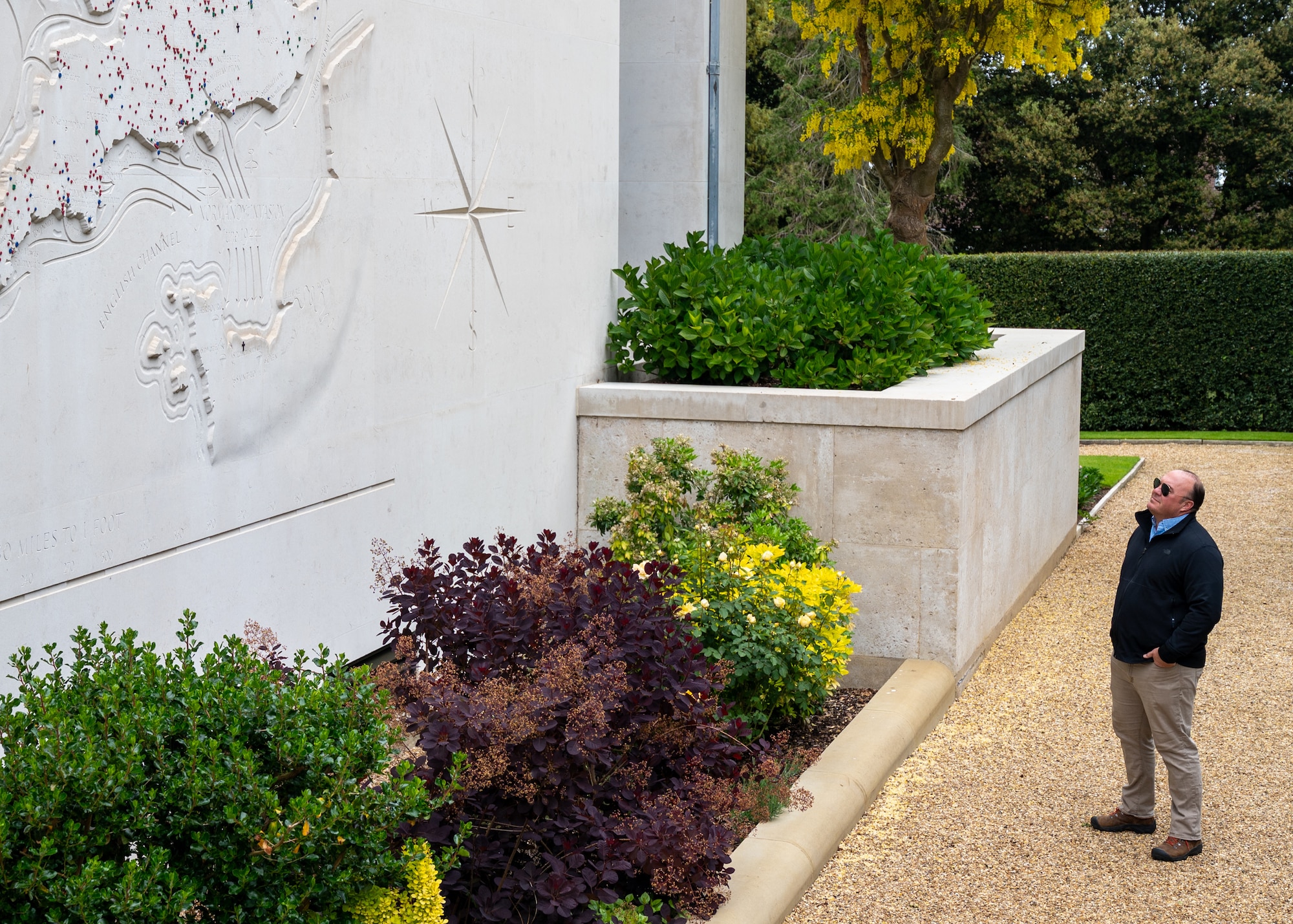 Male examines an engraved map on an exterior chapel wall
