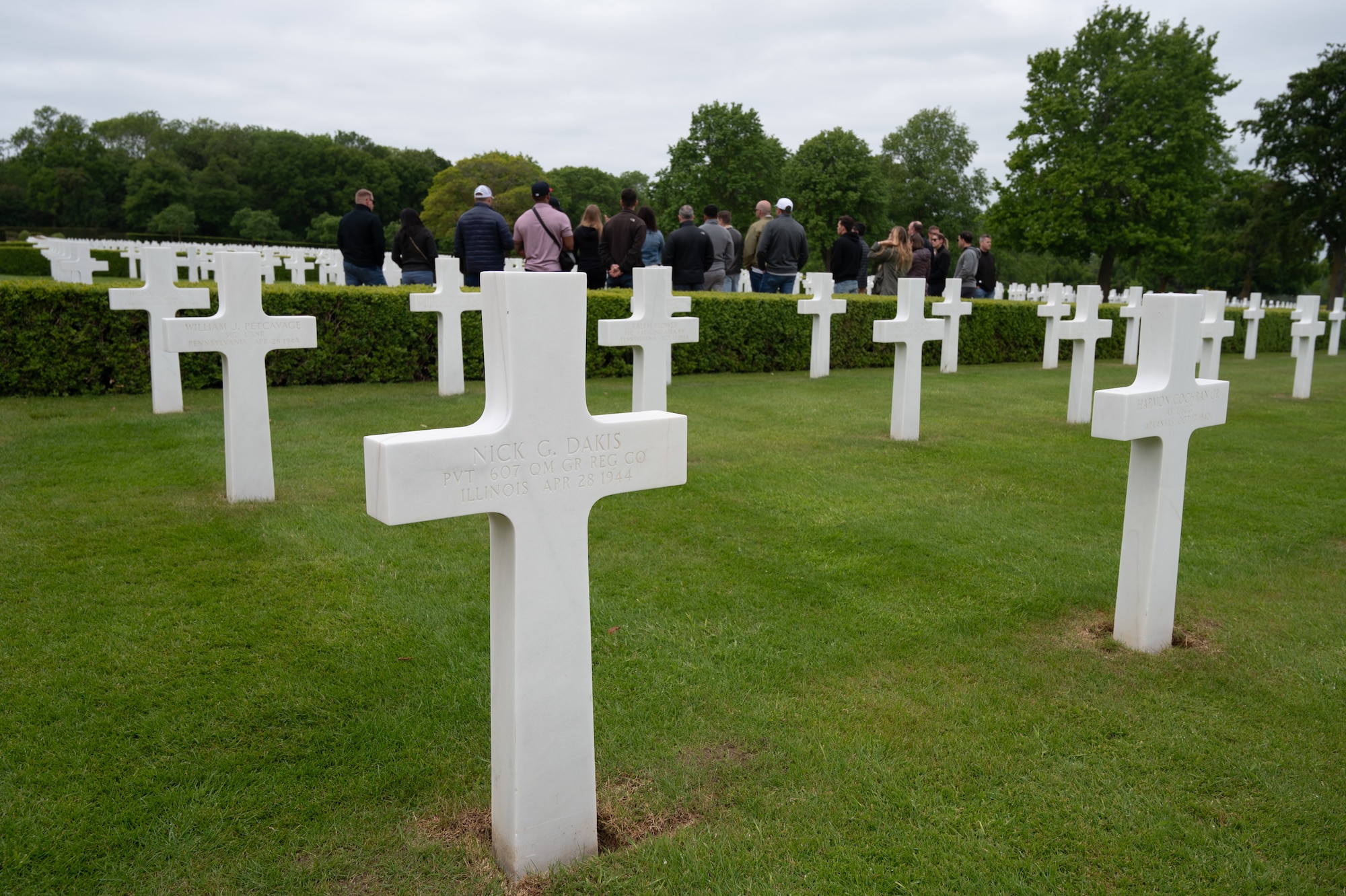 Individuals stand reflecting over headstones in a cemetery