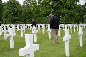 Individuals reflect next to headstones in a cemetery