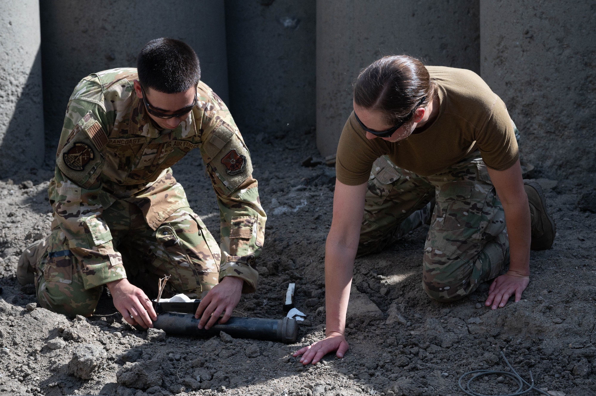 Senior Airman Arthur Pancoast, 5th Civil Engineer Squadron Explosive Ordnance Disposal journeyman, (left), and Capt. Natalie Petro, Explosive Ordnance Disposal flight commander, (right), attach a detonating cord to a shape charge at Minot Air Force Base, North Dakota, May 12, 2025. A detonating cord was used in this training exercise to properly control the detonation of the shape charge remotely. (U.S. Air Force photo by Airman 1st Class Wesley Davies)