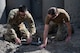 Senior Airman Arthur Pancoast, 5th Civil Engineer Squadron Explosive Ordnance Disposal journeyman, (left), and Capt. Natalie Petro, Explosive Ordnance Disposal flight commander, (right), attach a detonating cord to a shape charge at Minot Air Force Base, North Dakota, May 12, 2025. A detonating cord was used in this training exercise to properly control the detonation of the shape charge remotely. (U.S. Air Force photo by Airman 1st Class Wesley Davies)