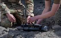 Senior Airman Arthur Pancoast, 5th Civil Engineer Squadron Explosive Ordnance Disposal (EOD) Journeyman, (left), and Capt. Natalie Petro, EOD flight commander, (right), prepare a shape charge to be detonated remotely at Minot Air Force Base, North Dakota, May 12, 2025. The event aimed to train new Airmen for the EOD flight in detonating shape charges and observe their effects. (U.S. Air Force photo by Airman 1st Class Wesley Davies)