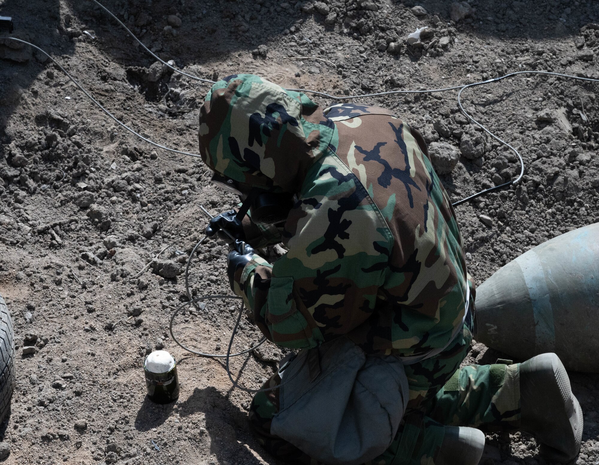 Airman 1st Class Robert Hobbs, 5th Civil Engineer Squadron Explosive Ordnance Disposal apprentice, sets up an improvised shape charge while in Mission Oriented Protective Posture level 4 at Minot Air Force Base, North Dakota, May 12, 2025. The event aimed to train new Airmen for the EOD flight in detonating shape charges and observe their effects. The EOD flight is tasked with  neutralizing hazards associated with explosive ordnance that pose a threat to people, installations, and operations. (U.S. Air Force photo by Airman 1st Class Wesley Davies)
