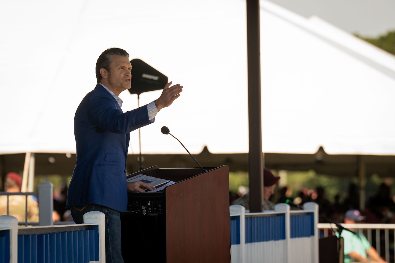 A man in civilian business attire speaks from a podium.