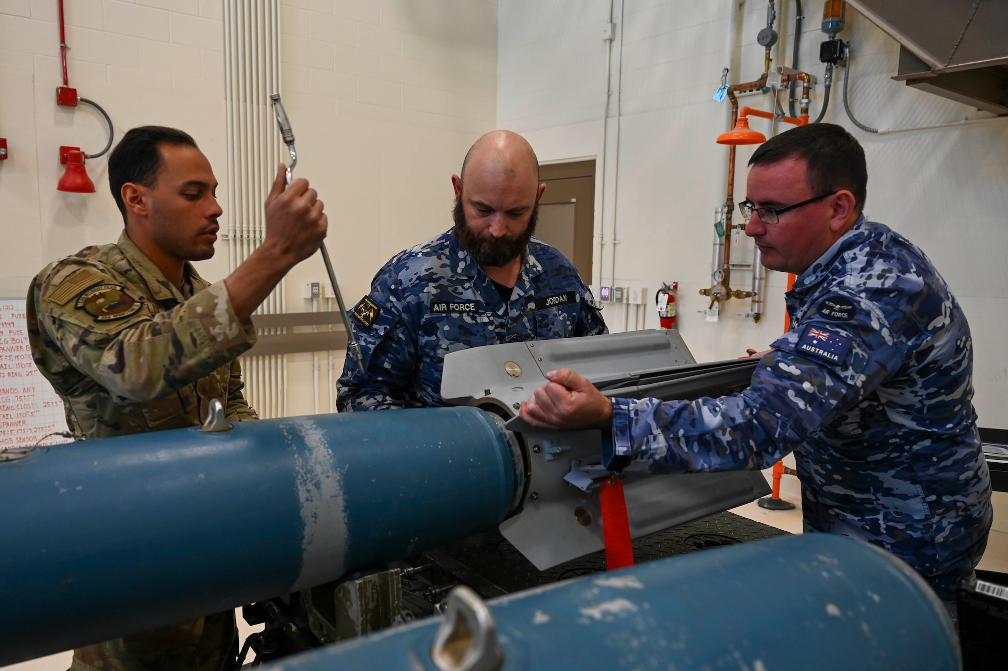 (From left to right) U.S. Air Force Senior Airman Theophilus Elisha, 354th Munitions Squadron conventional maintenance crew chief, Royal Australian Air Force Sgt. Clinton Jordan, 1st Squadron SNCO officer armament technician, and RAAF Cpl. Kurt Thompson, 1st Squadron NCO armament technician, assemble a GBU-12 Paveway II laser-guided dummy munition during a Combat Ammunition Production Exercise (CAPEX) at Eielson Air Force Base, Alaska, May 14, 2025.