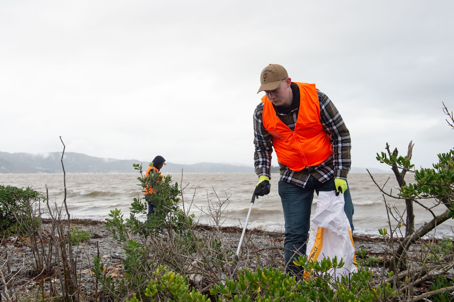 WELLINGTON, New Zealand (May 19, 2025) – Intelligence Specialist 2nd Class Ethan Comrie, assigned to U.S. 7th Fleet flagship USS Blue Ridge (LCC 19), participates in a beach clean-up event during a scheduled port visit in Wellington, New Zealand, May 19, 2025. The Blue Ridge and embarked U.S. 7th Fleet staff conduct regular Indo-Pacific patrols to deter aggression, strengthen alliances and partnerships, and advance future warfighting capabilities. (U.S. Navy photo by Mass Communication Specialist 3rd class Thomas Furnish)
