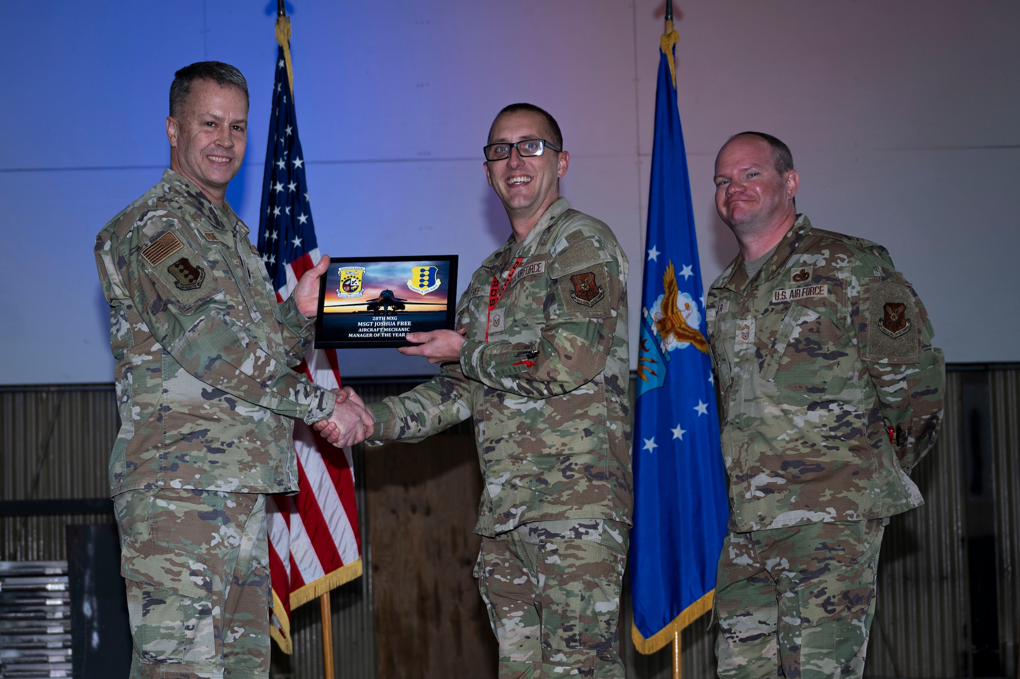 Lt. Col. Wilburn Poe, 28th Maintenance Group deputy commander and Chief Master Sgt. Daniel Werner, 37th Bomber Generation Squadron senior enlisted leader, present the 28th MXG Aircraft Mechanic Manager of the Year award to Master Sgt. Joshua Free, 34th Bomber Generation Squadron mechanic, at Grand Forks Air Force Base, N.D., April 25, 2025. There were approximately 37 awards presented during the ceremony, to acknowledge airmen who went above and beyond while serving in maintenance roles. (U.S. Air Force photo by Airman 1st Class Emma Funderburk)