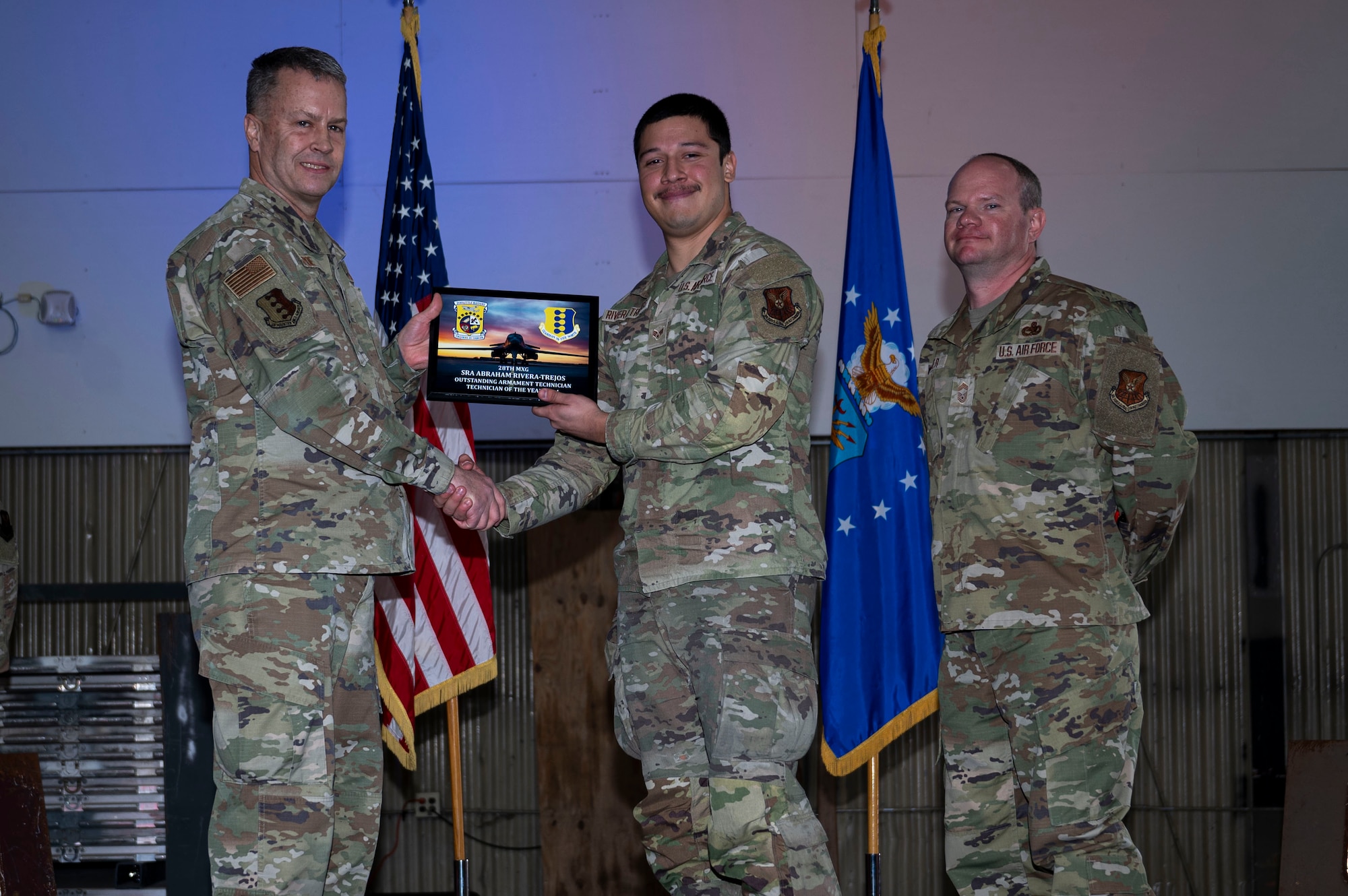 Lt. Col. Wilburn Poe, 28th Maintenance Group deputy commander, and Chief Master Sgt. Daniel Werner, 37th Bomber Generation Squadron senior enlisted leader, present the 28th MXG Technician of the Year award to Senior Airman Abraham Rivera-Trejos, 34th Bomber generation Squadron armament technician, at Grand Forks Air Force Base, N.D., April 25, 2025. During the ceremony, Airmen were recognized for their dedication to mission generation and supporting U.S. Air Force readiness and lethality. (U.S. Air Force photo by Airman 1st Class Emma Funderburk)