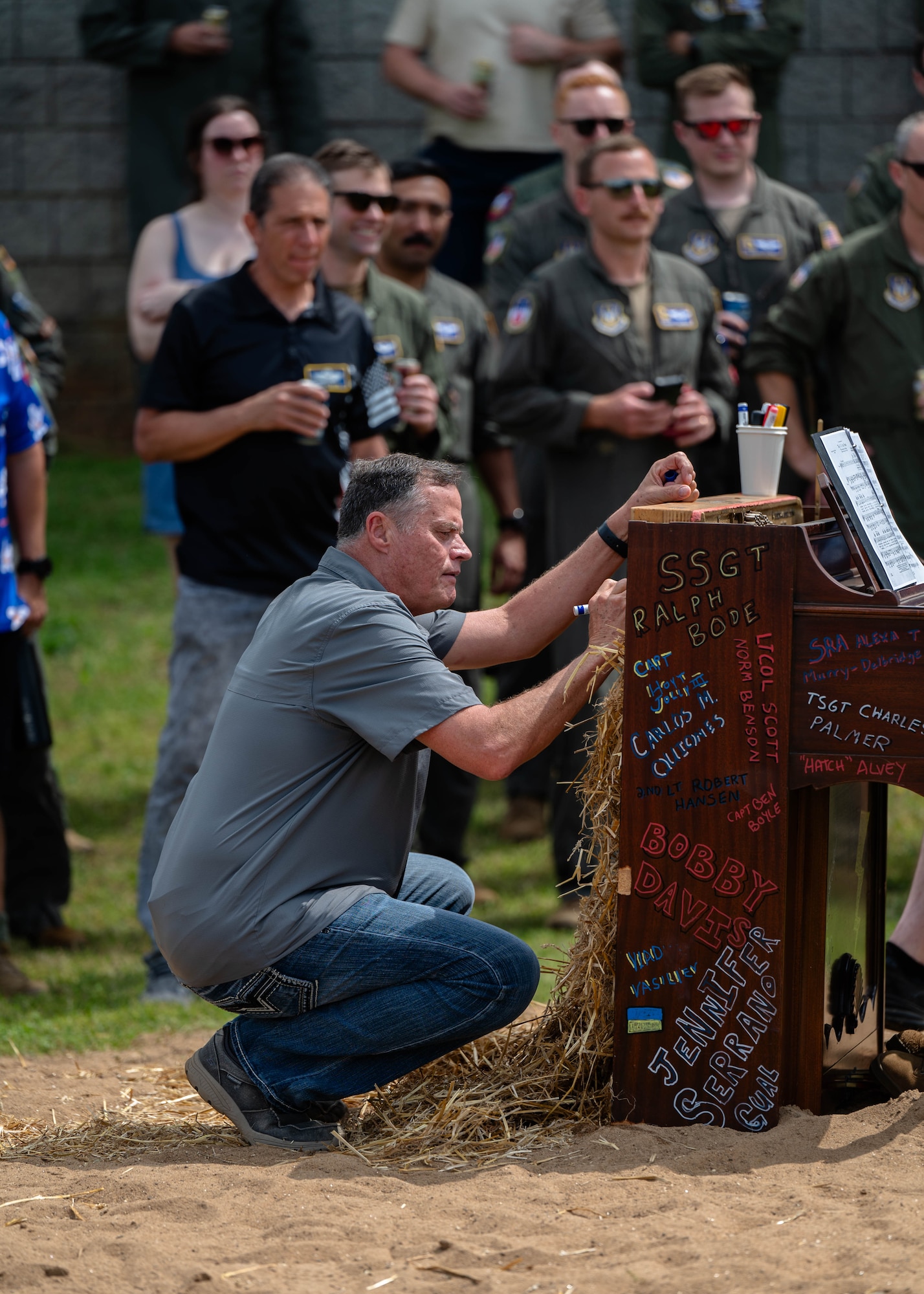 A man writes a name on a piano before its ceremonial burning at Dobbins Air Reserve Base